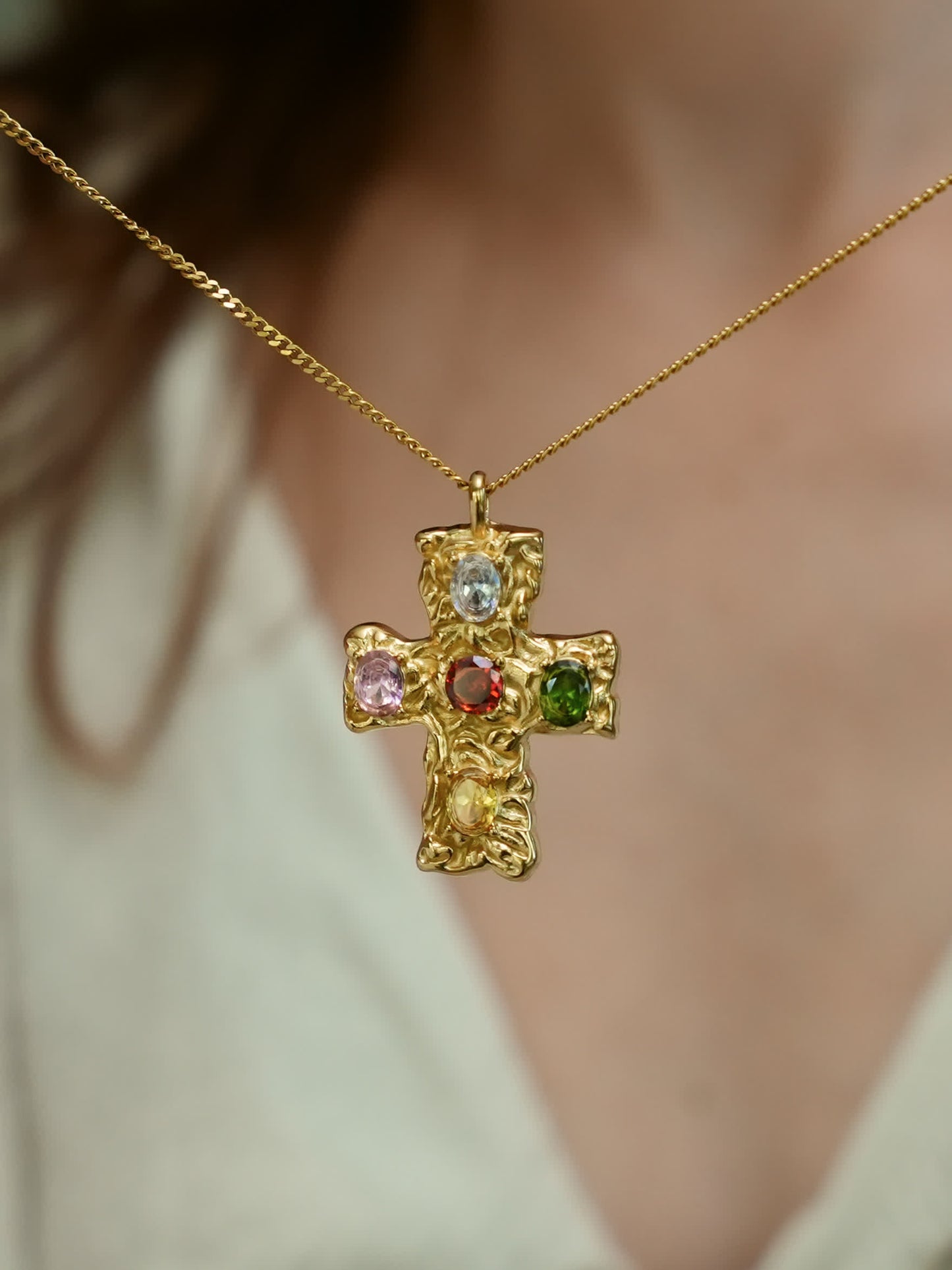 Sculptural multicolor cross necklace worn close to heart, showcasing Christian faith and vibrant design