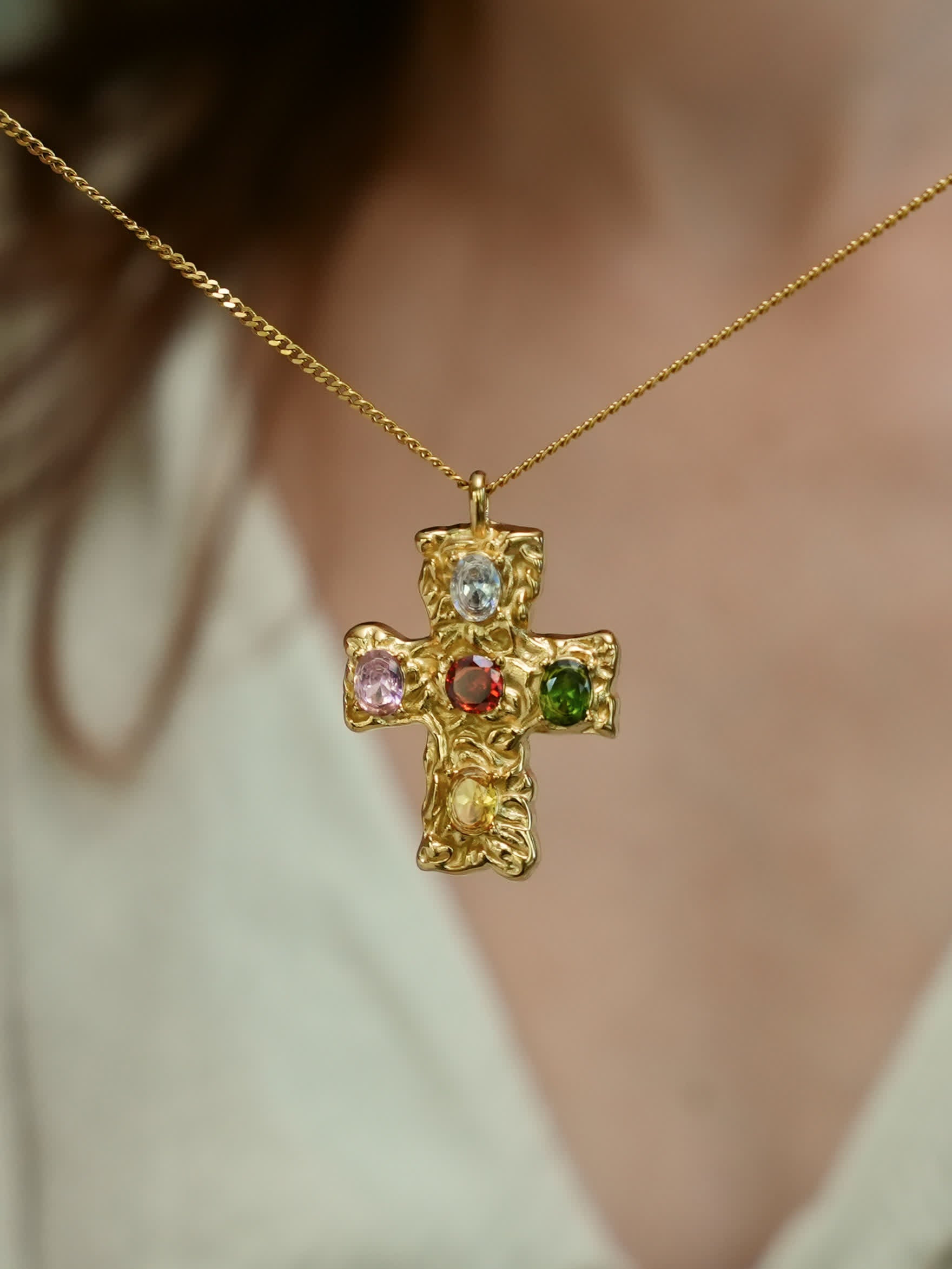 Sculptural multicolor cross necklace worn close to heart, showcasing Christian faith and vibrant design