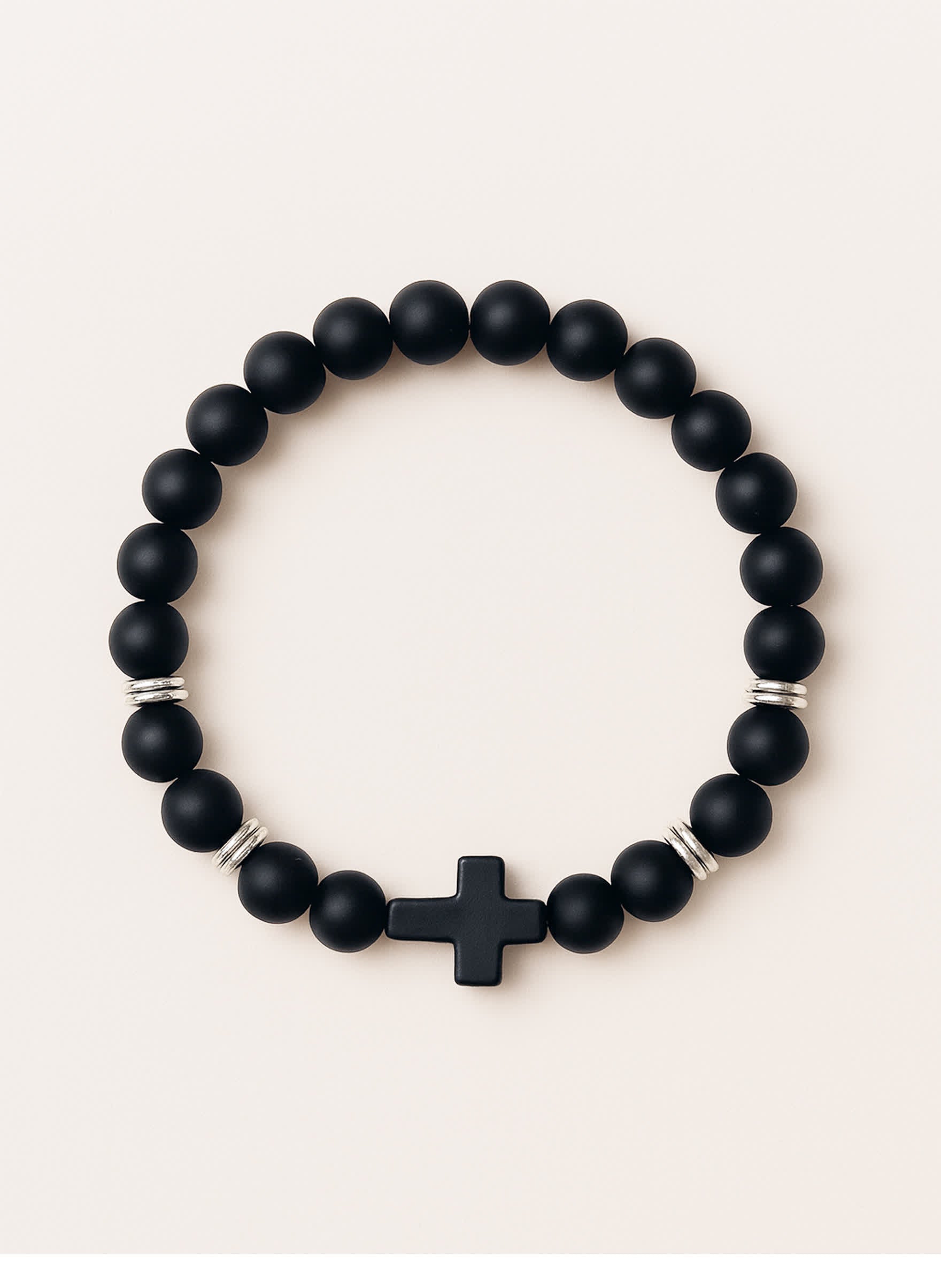 Studio product photo of the Covenant Shield Men's Cross Bracelet with matte black gemstone beads and a centered black cross, displayed against a soft cream background.