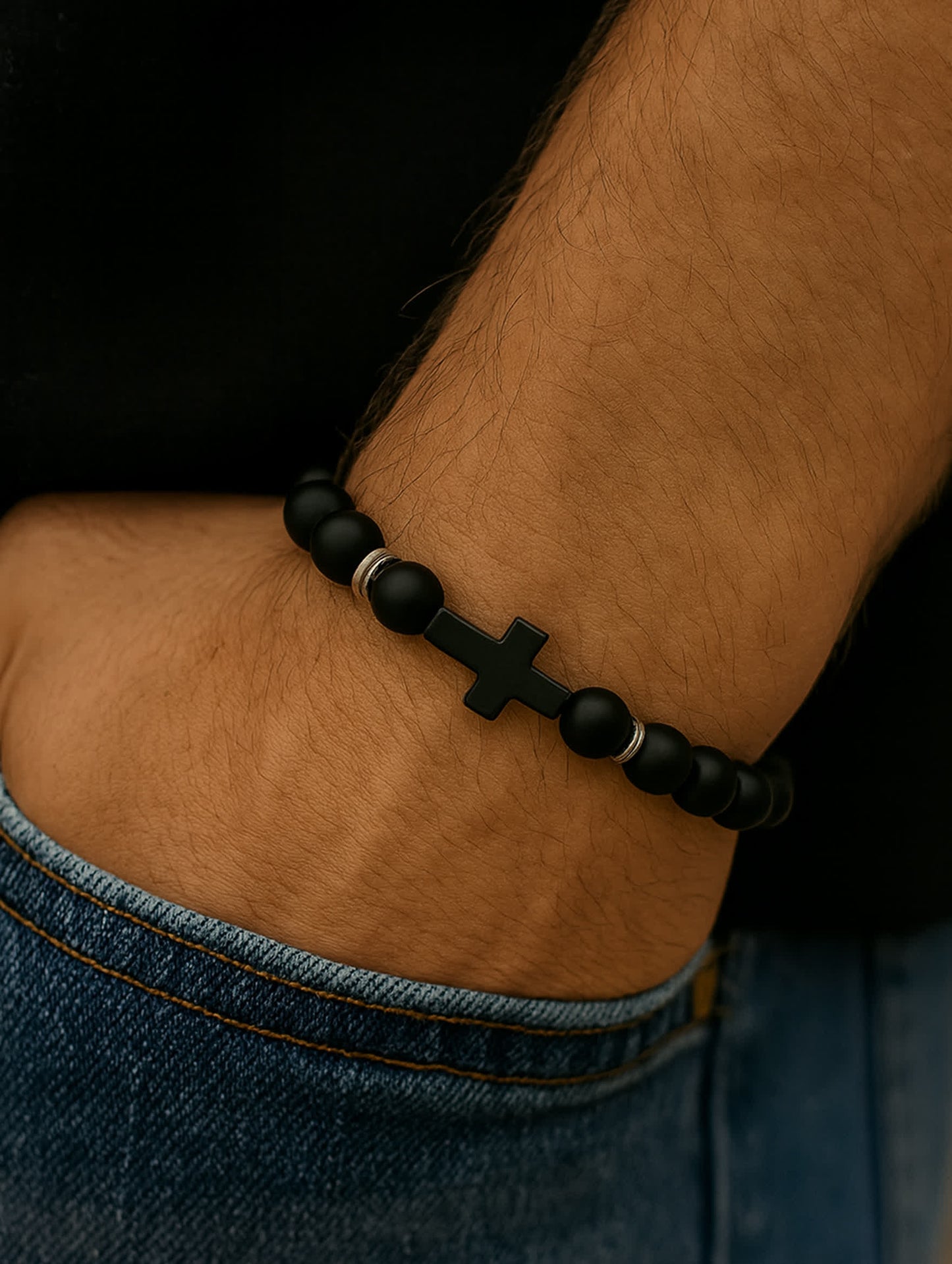 Lifestyle photo of the Covenant Shield Men's Cross Bracelet worn on a man's wrist with jeans and a black shirt, emphasizing the rugged, faith-centered style.