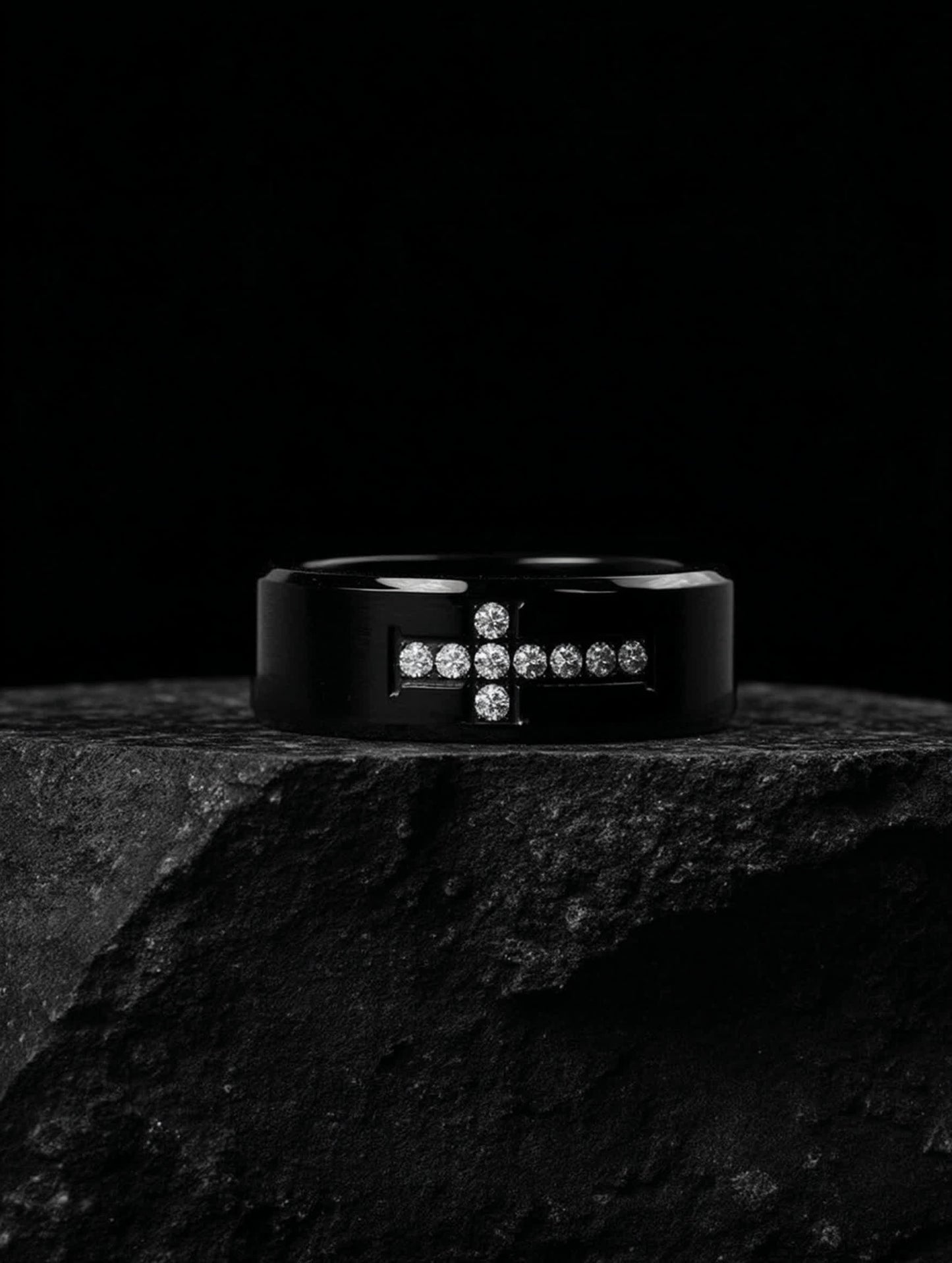 Creed Noir Black Cross Ring on black stone slab, dramatic lighting highlighting the contrast between the black surface and white crystals.
