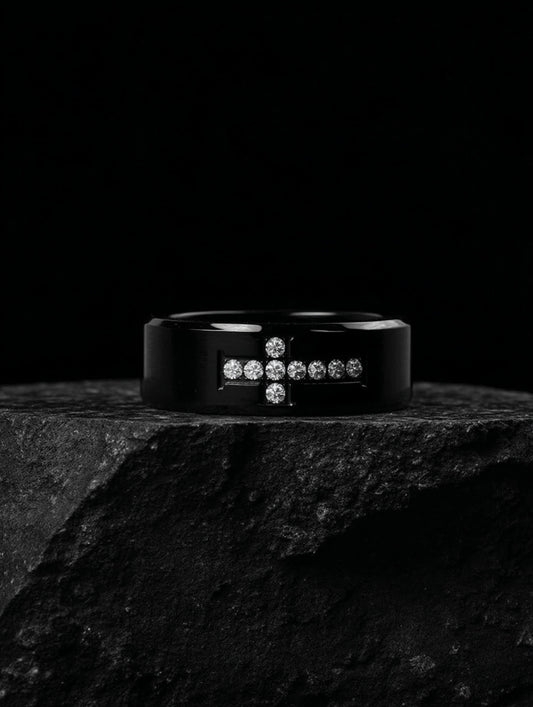 Creed Noir Black Cross Ring on black stone slab, dramatic lighting highlighting the contrast between the black surface and white crystals.