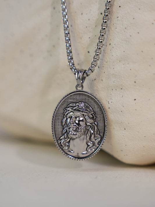 Faith necklace with Jesus portrait and crown of thorns displayed against a textured ceramic prop, showcasing fine craftsmanship.