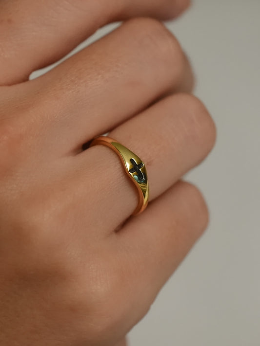 Minimalist gold cross ring with black inlay shown on model’s hand from side angle