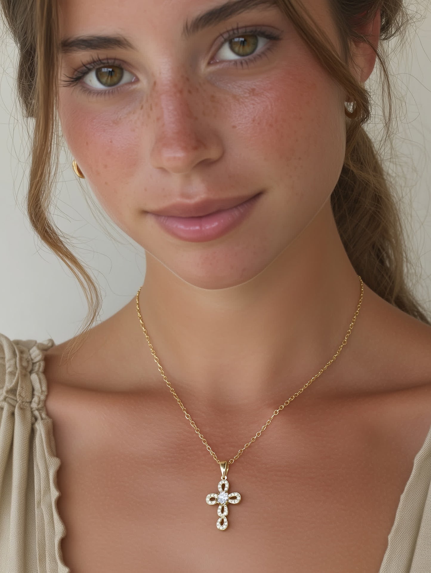 Model wearing elegant loop cross necklace with gold chain and feminine neckline