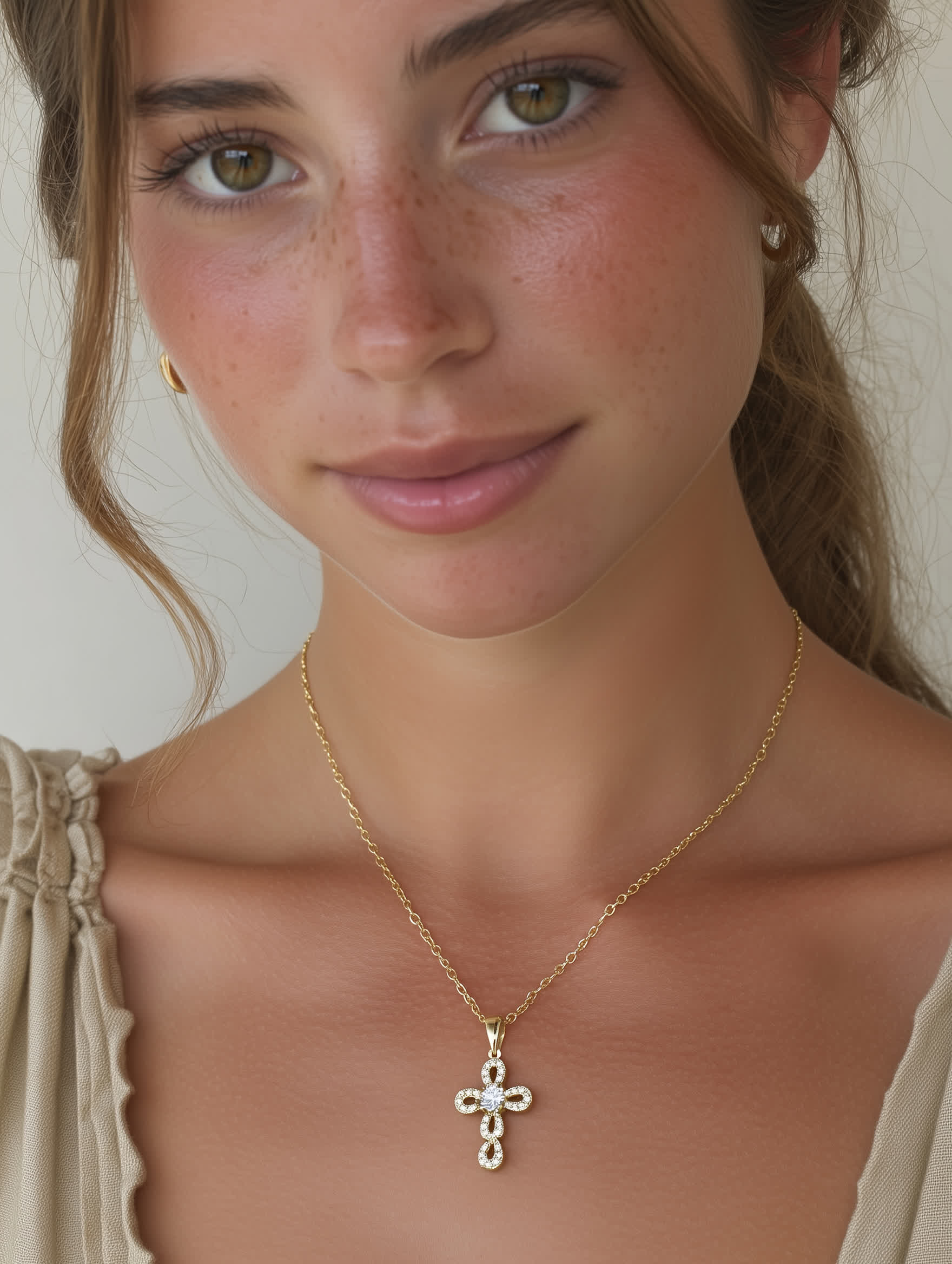 Model wearing elegant loop cross necklace with gold chain and feminine neckline