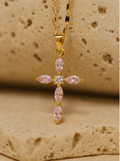 Close-up of pink cross necklace with marquise-cut zircon stones resting on natural stone surface