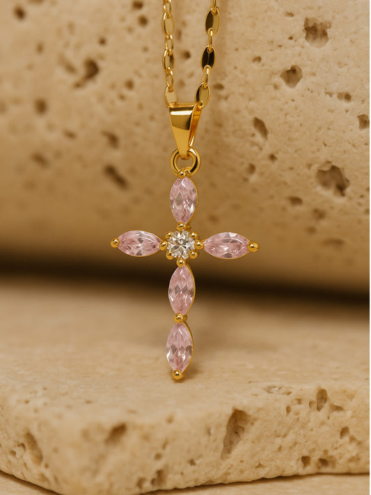 Close-up of pink cross necklace with marquise-cut zircon stones resting on natural stone surface