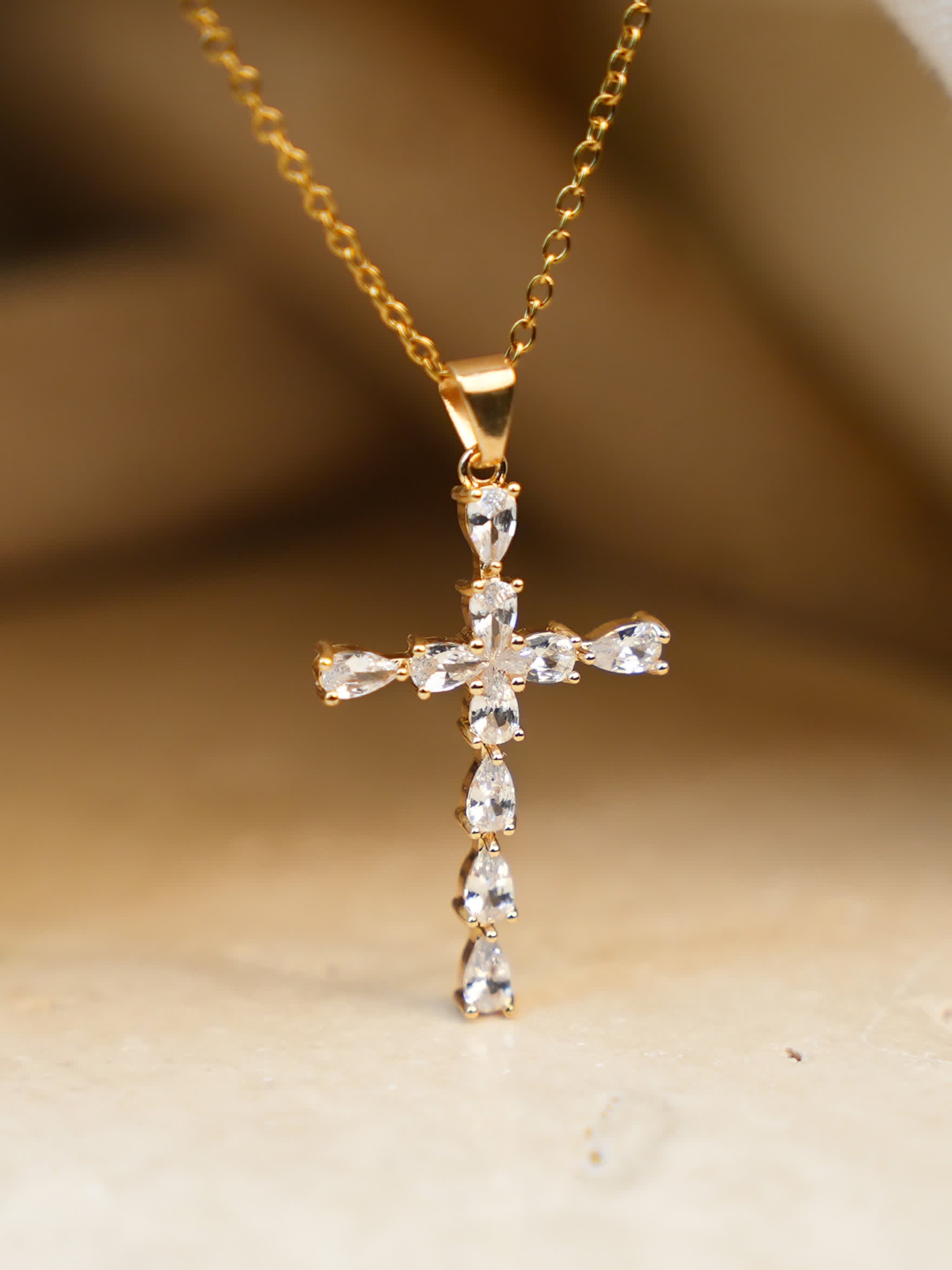 Teardrop-accented gold pendant displayed under soft light on natural fabric, emphasizing crystal clarity