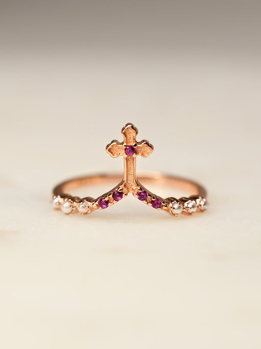 Close-up of rose gold ring with cross and cubic zirconias on cream stone surface