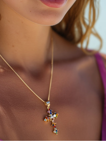 Model wearing necklace showing the colorful cross pendant against her neckline, demonstrating fit and radiant sparkle