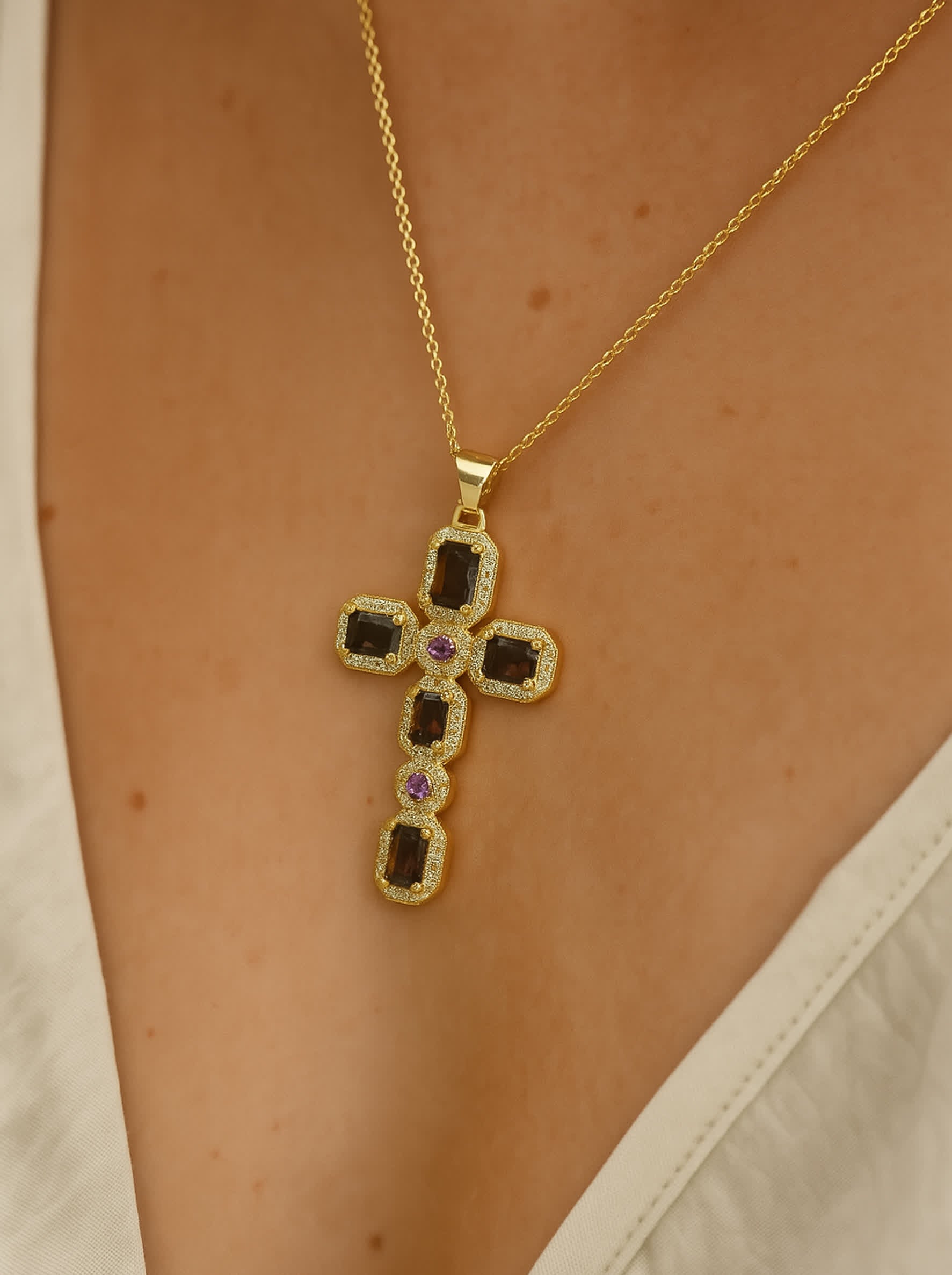 Model wearing the Faithstone zircon cross necklace, pendant centered at chest over a cream V-neck blouse