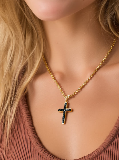 Woman wearing black stone cross necklace with gold chain over rust-colored top