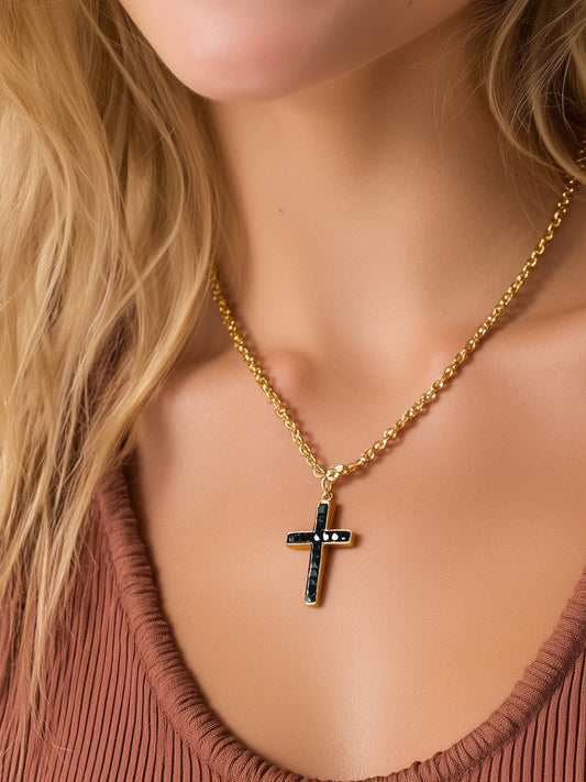 Woman wearing black stone cross necklace with gold chain over rust-colored top