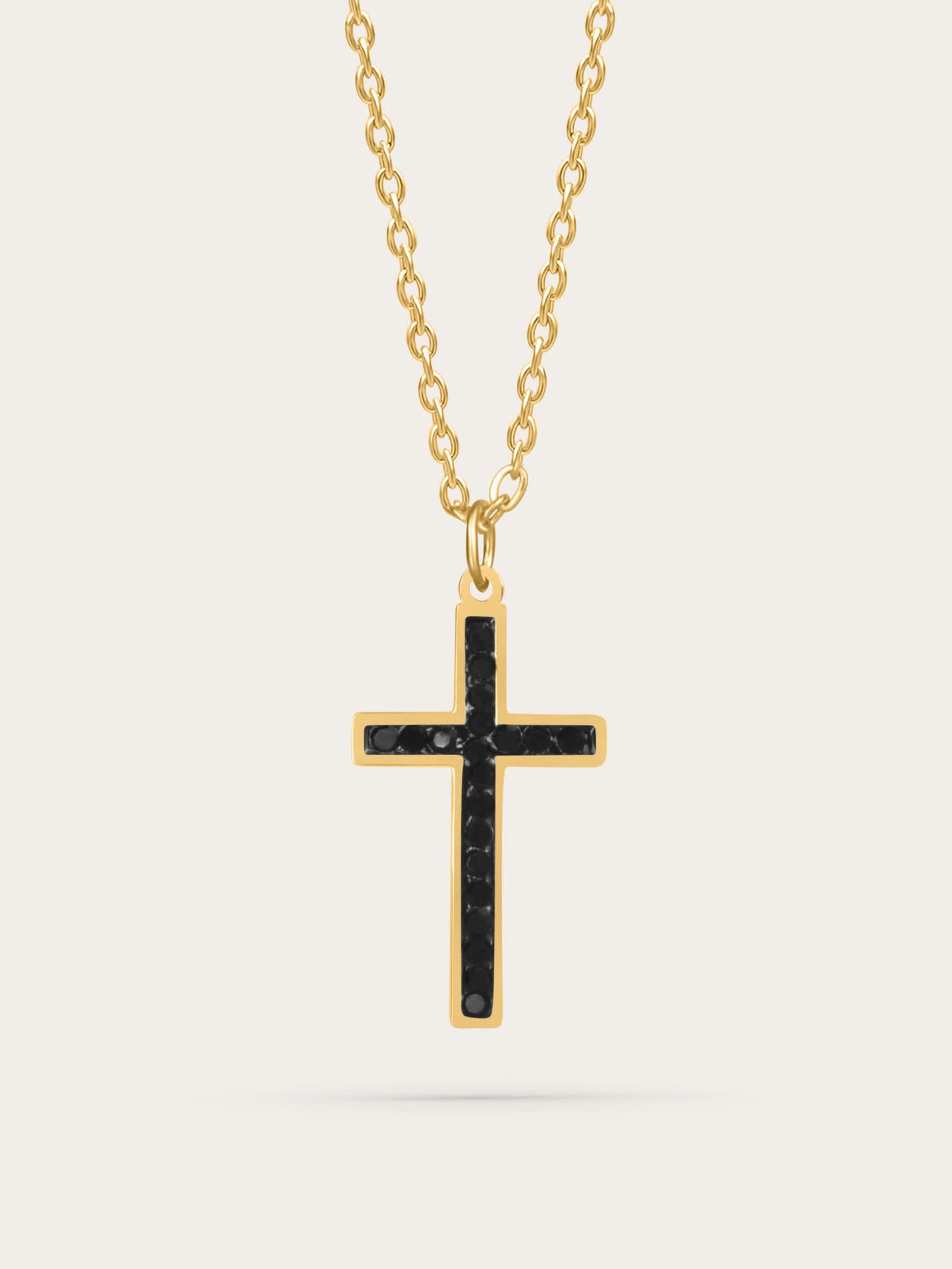 Gold cross necklace with black zircon stones displayed on light background