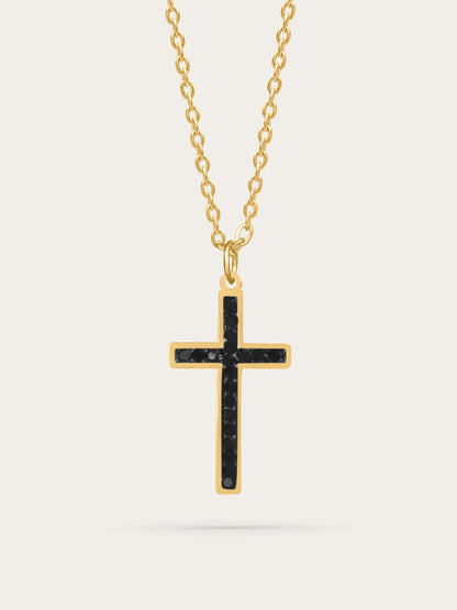 Gold cross necklace with black zircon stones displayed on light background