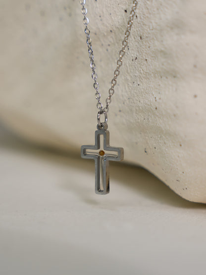 Close-up of necklace on textured stone
Silver mustard seed cross necklace resting on smooth white stone surface