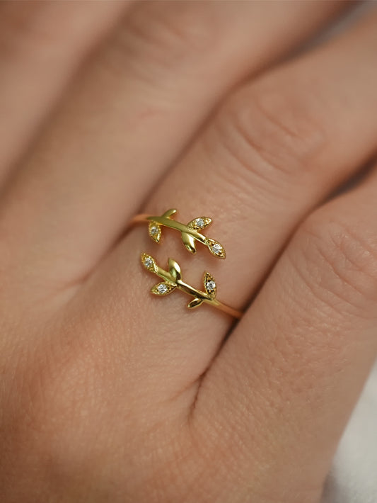 18K gold olive leaf ring worn on hand with soft lighting
