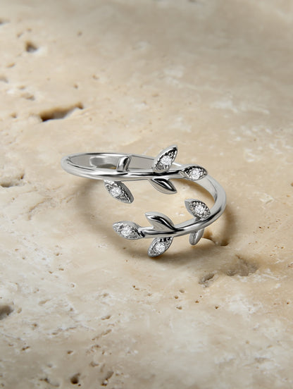 Olive leaf silver ring placed on a natural travertine slab, showcasing its organic shape and shimmering stones.