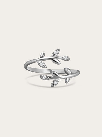 Sterling silver olive branch ring with cubic zirconia leaves on a cream background, minimal studio lighting.