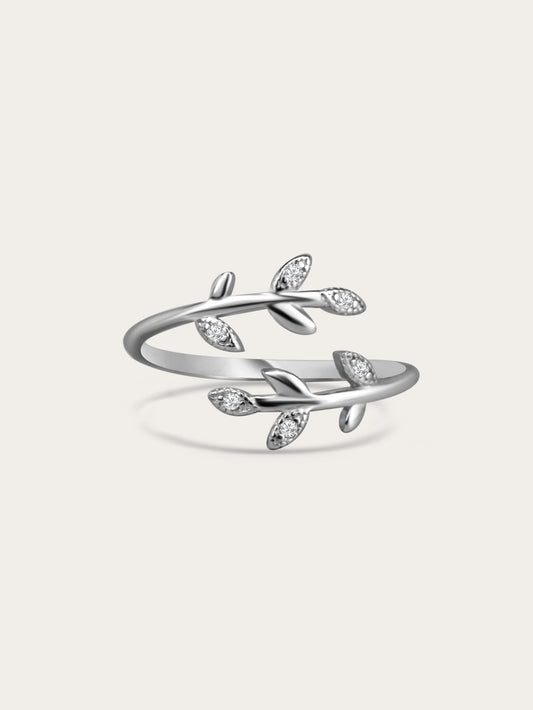 Sterling silver olive branch ring with cubic zirconia leaves on a cream background, minimal studio lighting.