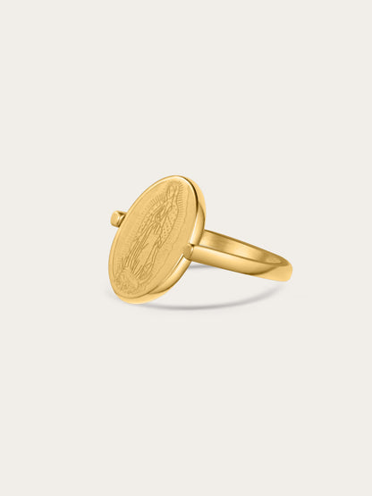 Angled view of gold Our Lady ring with engraved Virgin Mary on oval medallion, shown on a light background