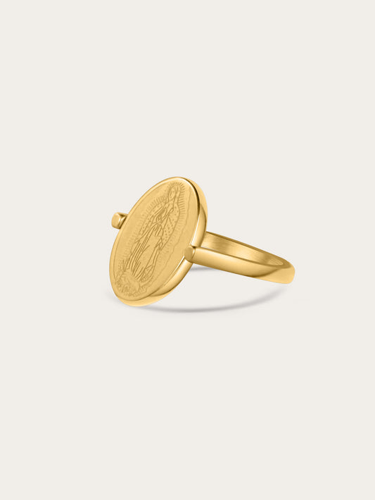 Angled view of gold Our Lady ring with engraved Virgin Mary on oval medallion, shown on a light background