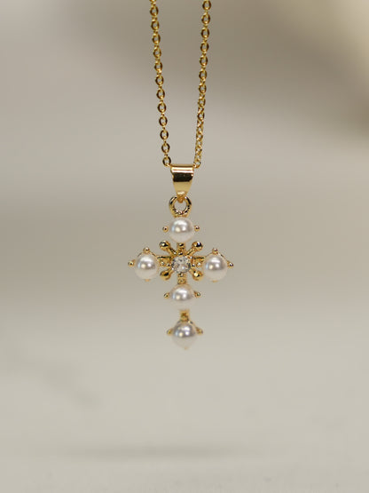 Gold floral cross pendant with resin pearls and crystal center on white background