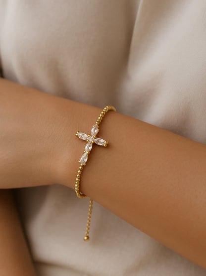 Lifestyle photo of the Radiant Mercy Gold Cross Bracelet worn on a woman's wrist, capturing the graceful drape and refined sparkle of the adjustable gold bracelet.