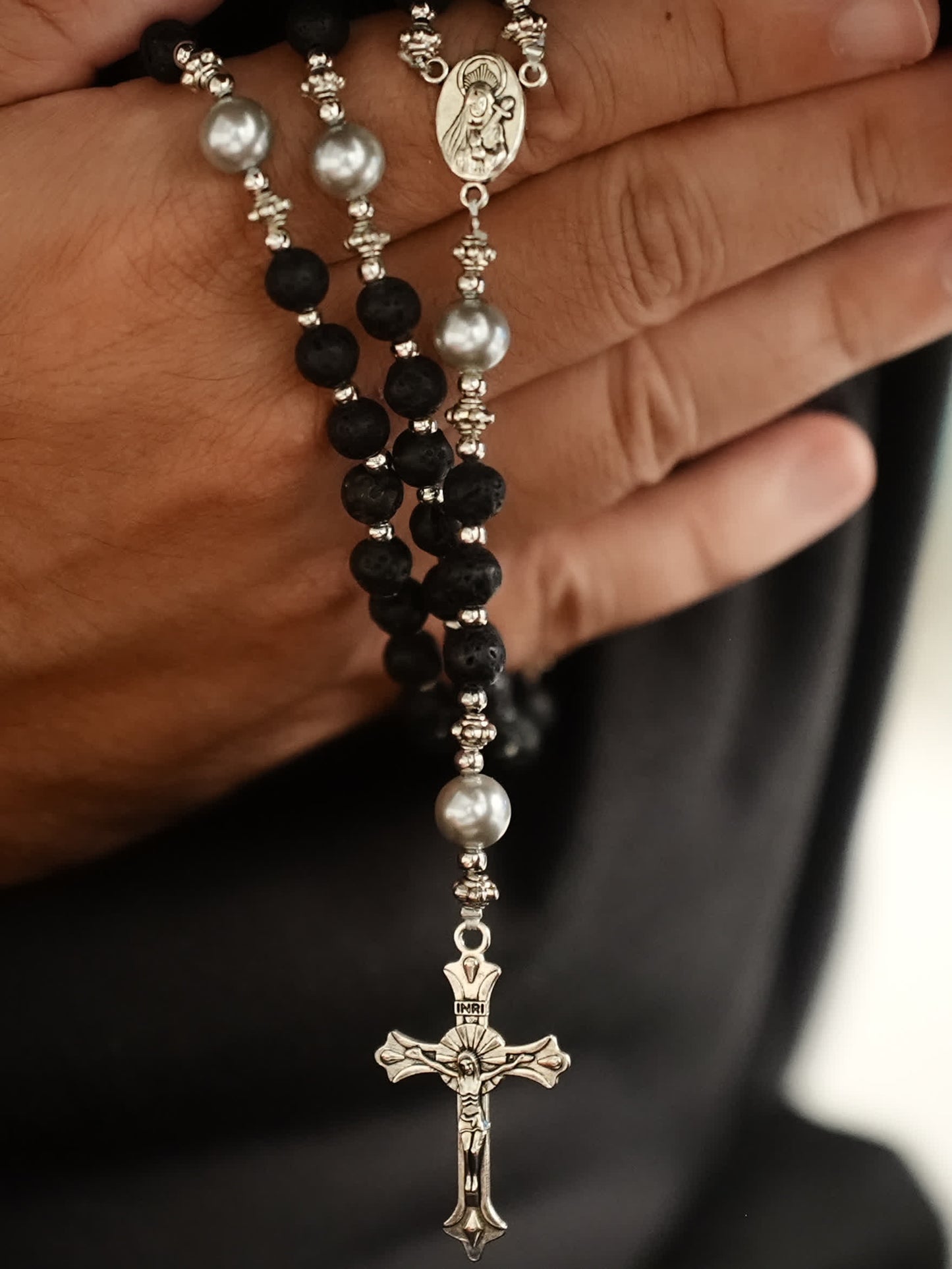 black lava rosary necklace with silver cross on neutral background
