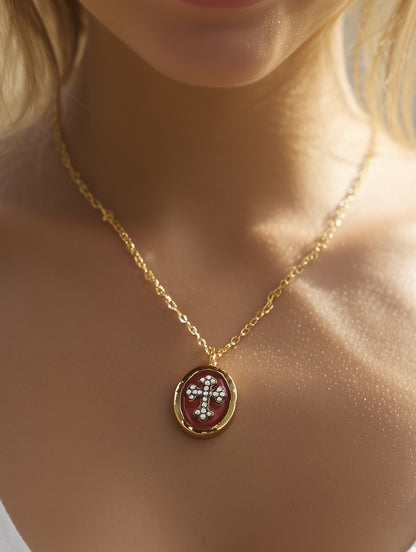 Woman wearing crimson enamel cross pendant necklace at collarbone