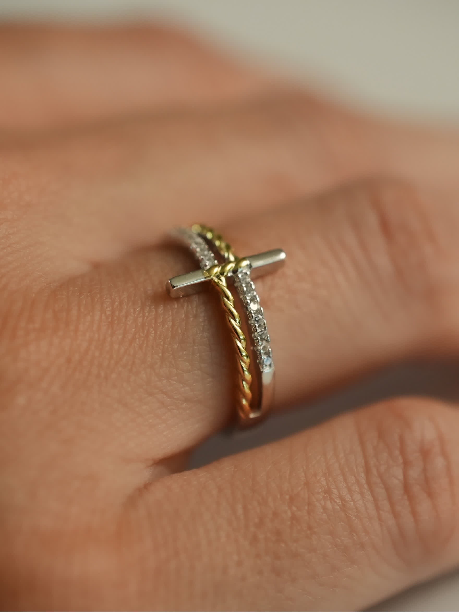 Lifestyle image of silver and gold cross wrap ring on model’s hand, showcasing spiritual and minimalist aesthetic