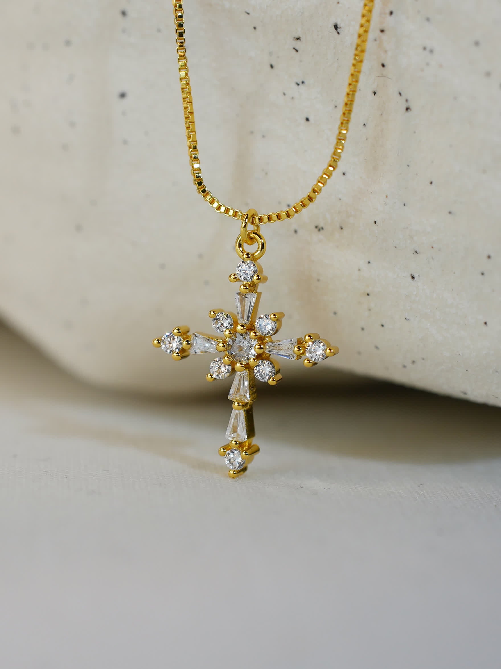 Blooming cross necklace resting on ivory stone surface, highlighting sparkling crystal arrangement