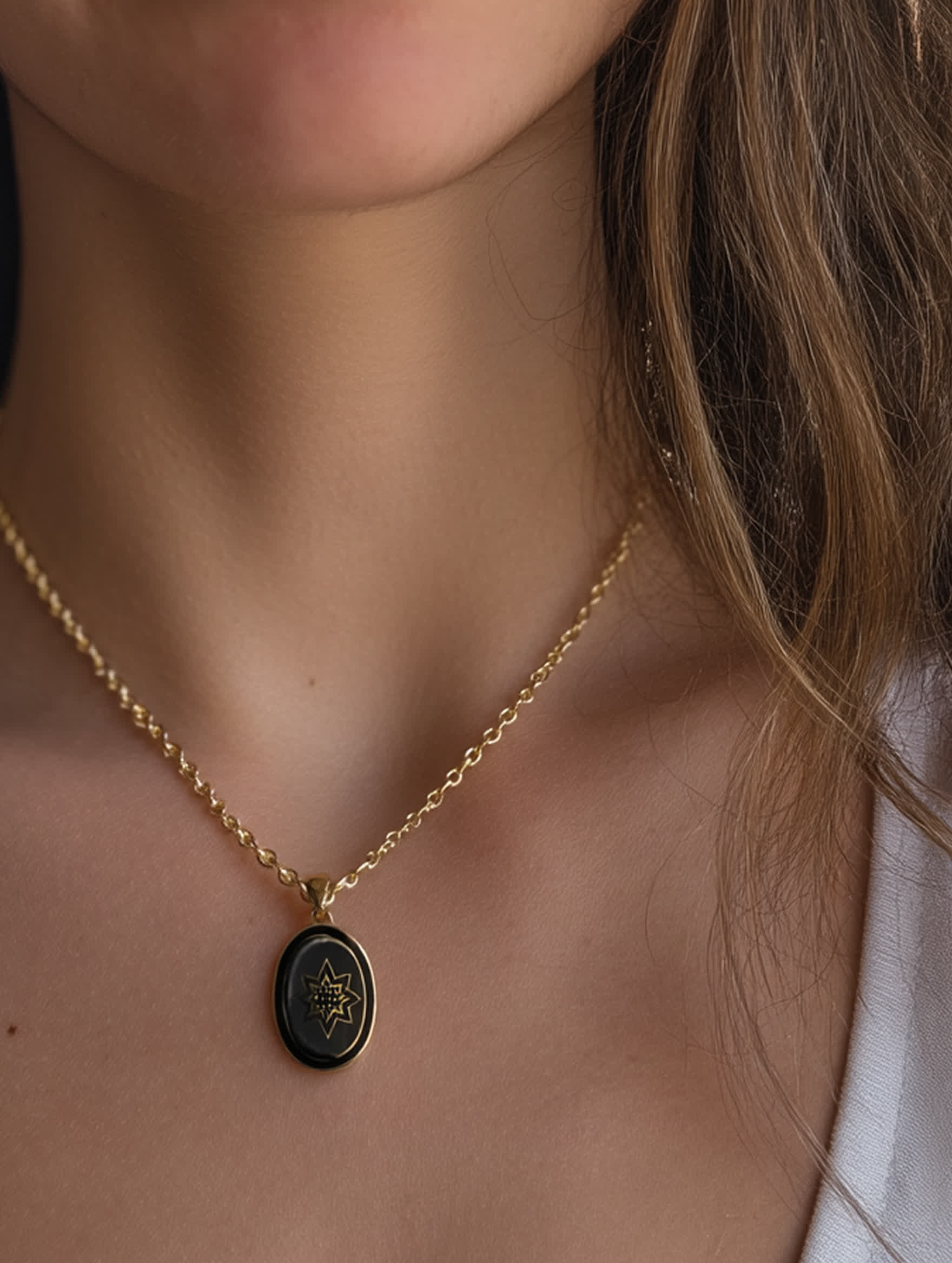 Bethlehem star necklace worn on model showing delicate gold chain and black enamel pendant