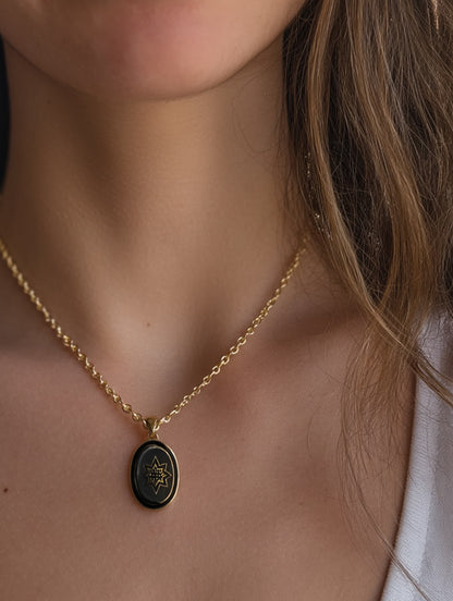 Bethlehem star necklace worn on model showing delicate gold chain and black enamel pendant
