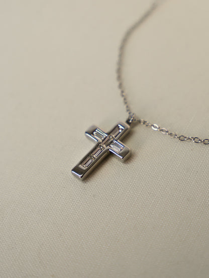 Close-up of baguette zircon cross pendant lying on cream fabric