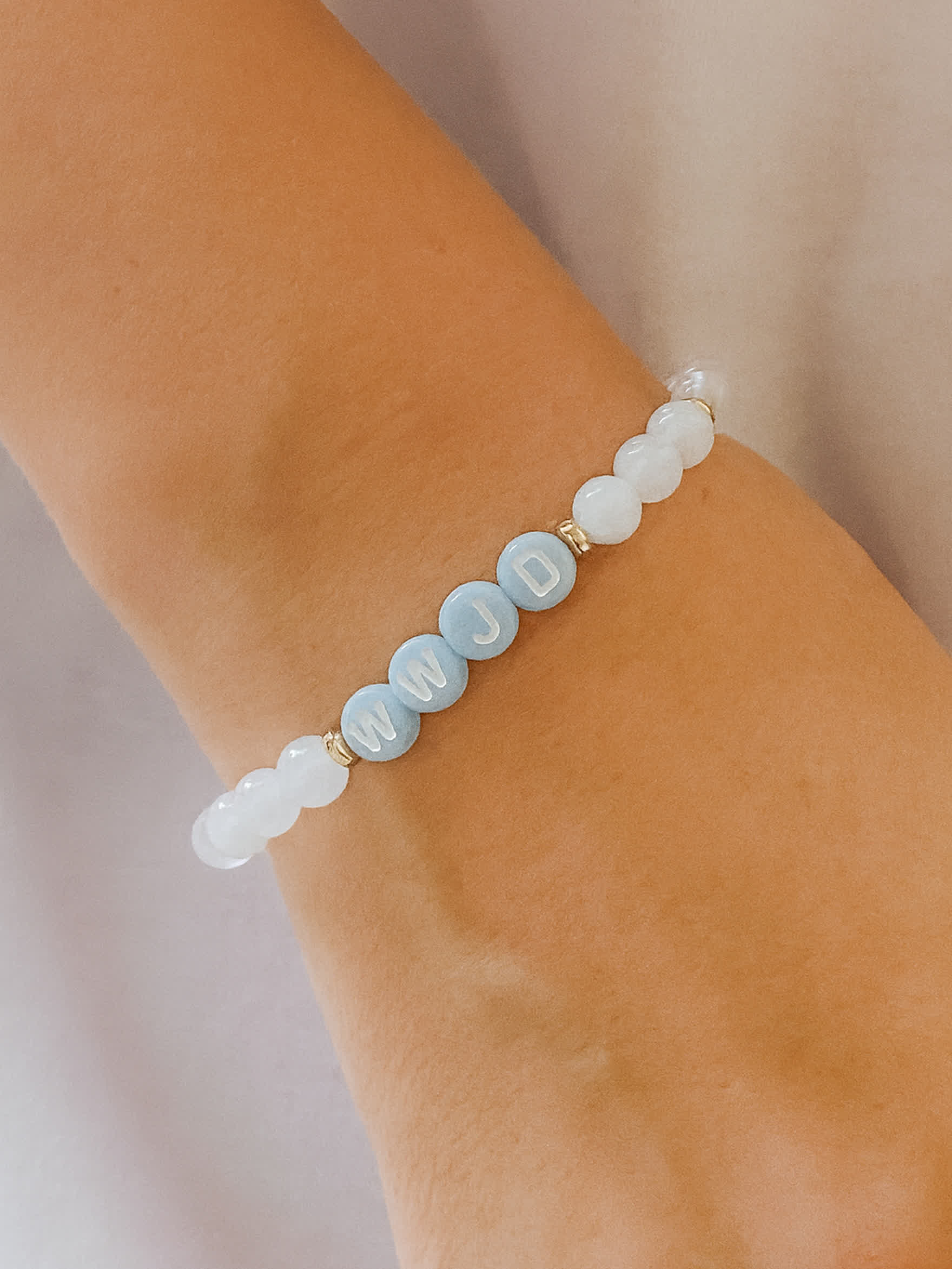 Lifestyle photo of the Quiet Steps WWJD Bracelet worn on a woman’s wrist, showing the stretch fit and peaceful design in soft natural lighting.
