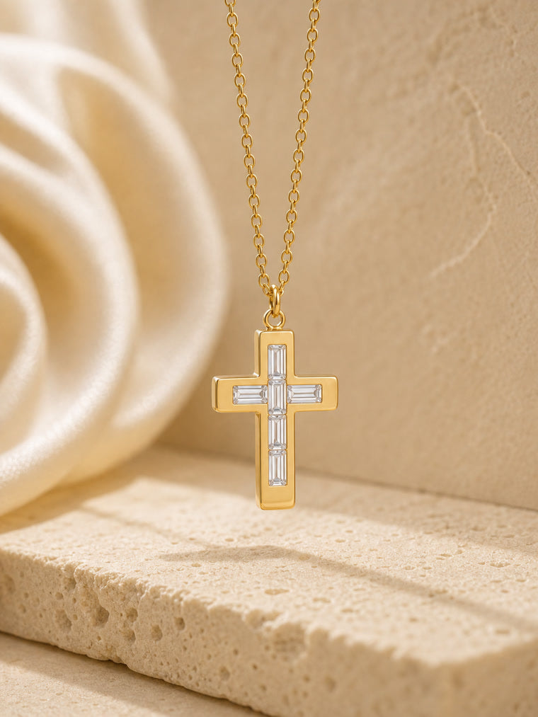 Gold cross necklace with diamond accents on a beige stone surface