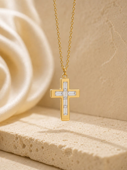 Gold cross necklace with diamond accents on a beige stone surface