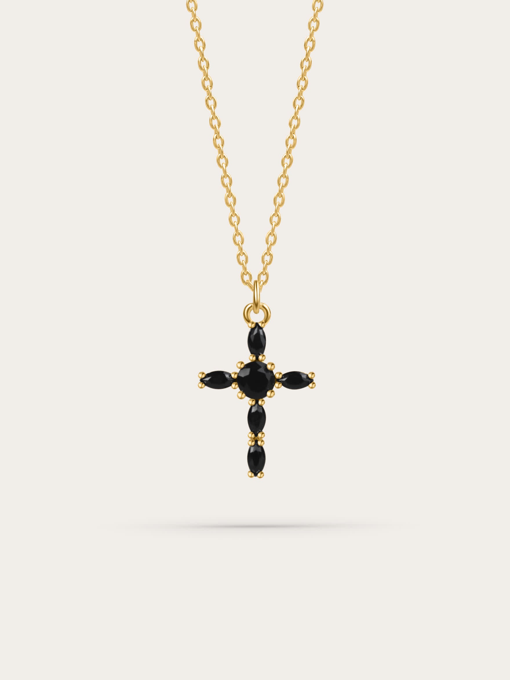 Studio photo of a black zircon marquise gold cross necklace on white background
