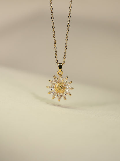 Gold-plated sunflower pendant with sparkling zircon stones photographed on soft beige fabric